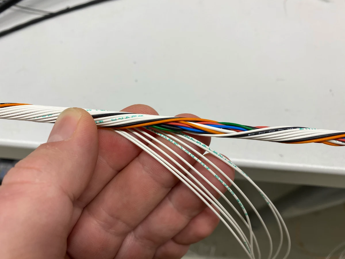 Concentric twisting a motorsport wiring bundle by hand — alternating twist directions build a round, tight loom